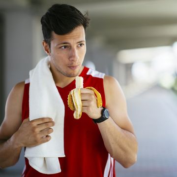 athletic man eating banana after workout outdoors