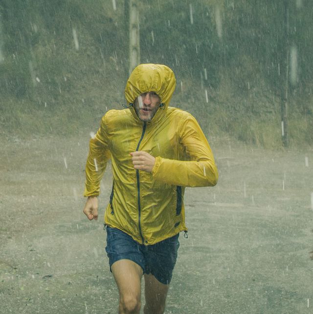 athletic man jogging in extreme weather condition hail and rain