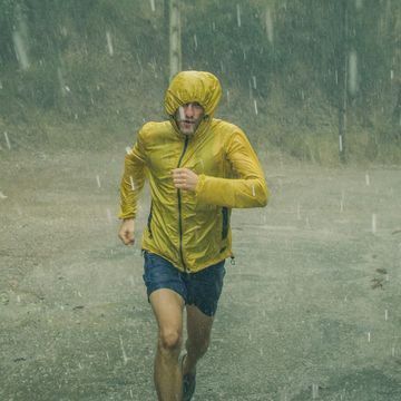 athletic man jogging in extreme weather condition hail and rain