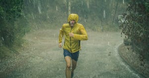 athletic man jogging in extreme weather condition hail and rain