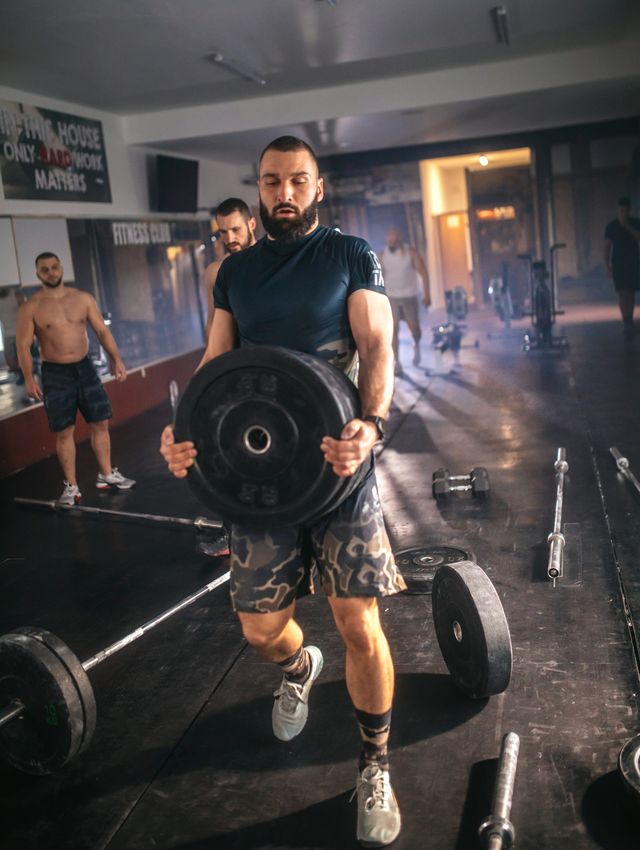 athletic people having cross training with dumbells in a gym