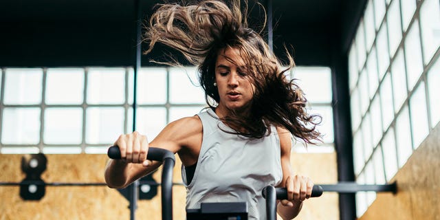 Athletic woman doing air bike workout at gym