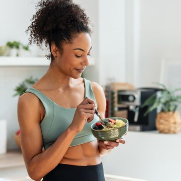 athletic woman eating a healthy fruit bowl in the kitchen at home