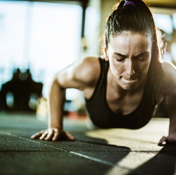 athletic woman making an effort while exercising push ups in a gym.