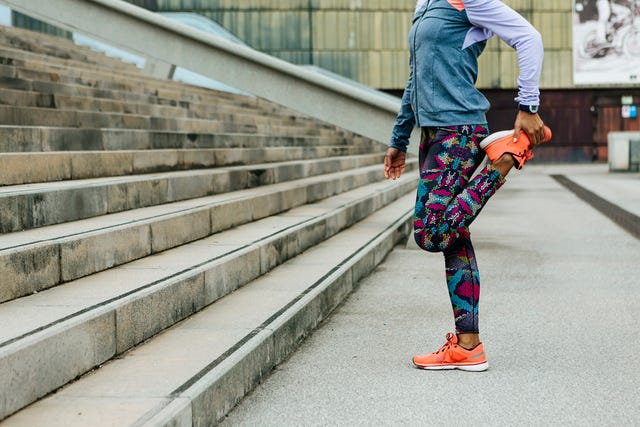 athletic woman n workout clothes stretching legs before running