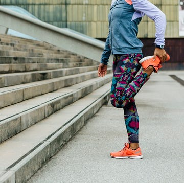 athletic woman n workout clothes stretching legs before running