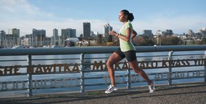 athletic young woman jogs along city river