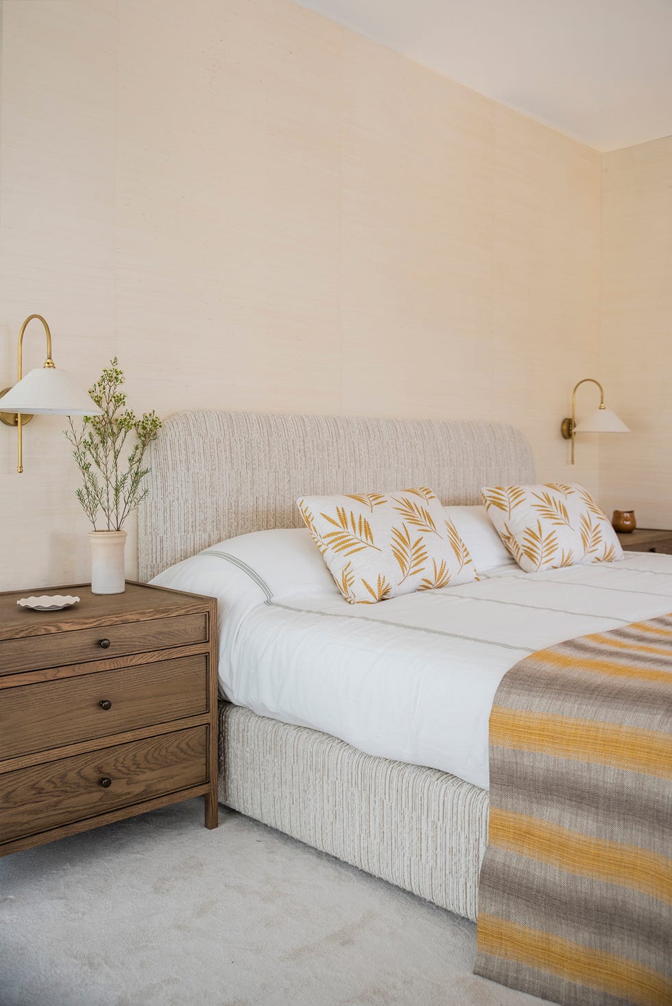 cama tapizada en tela beige y mesitas de madera