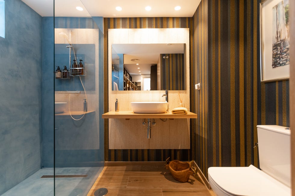 baño con ducha de obra y papel pintado a rayas