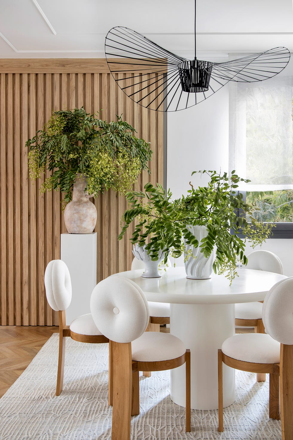 mesa de comedor redonda con sillas de madera y tapizado blanco