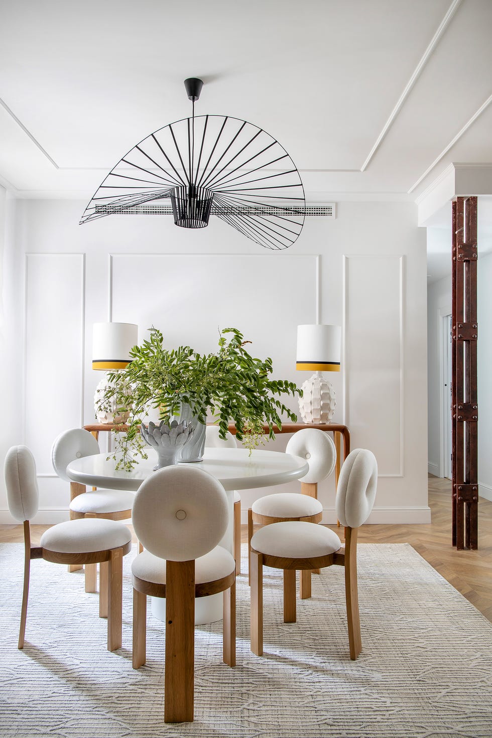 mesa de comedor redonda con sillas de madera y tapizado blanco