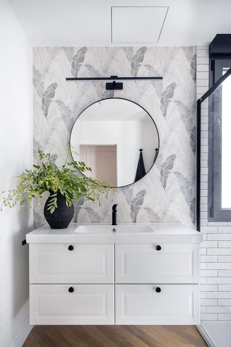 baño con mueble volado de madera rústico y papel pintado con motivos de hojas