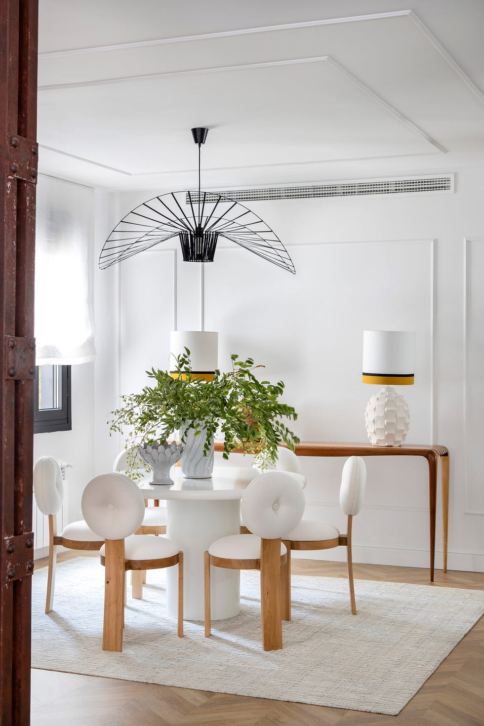 mesa de comedor redonda con sillas de madera y tapizado blanco