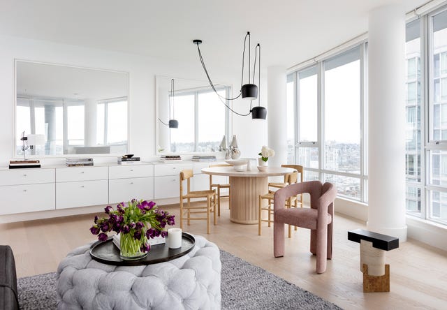 salón comedor con reposapiés acolchado gris y mesa redonda de madera