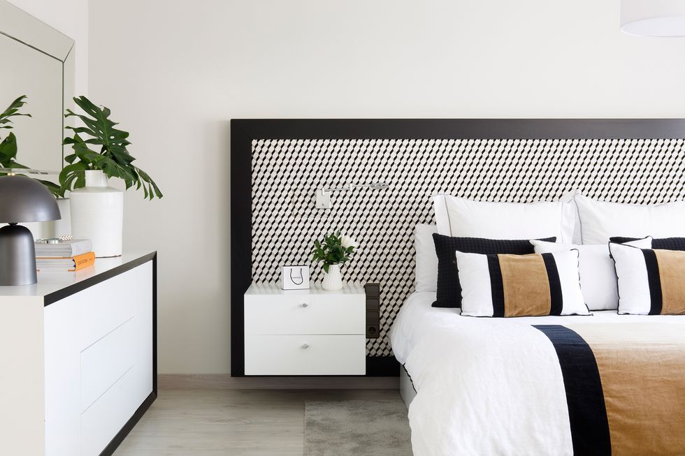dormitorio moderno con cabecero geométrico en blanco y negro y mesitas de noche suspendidas