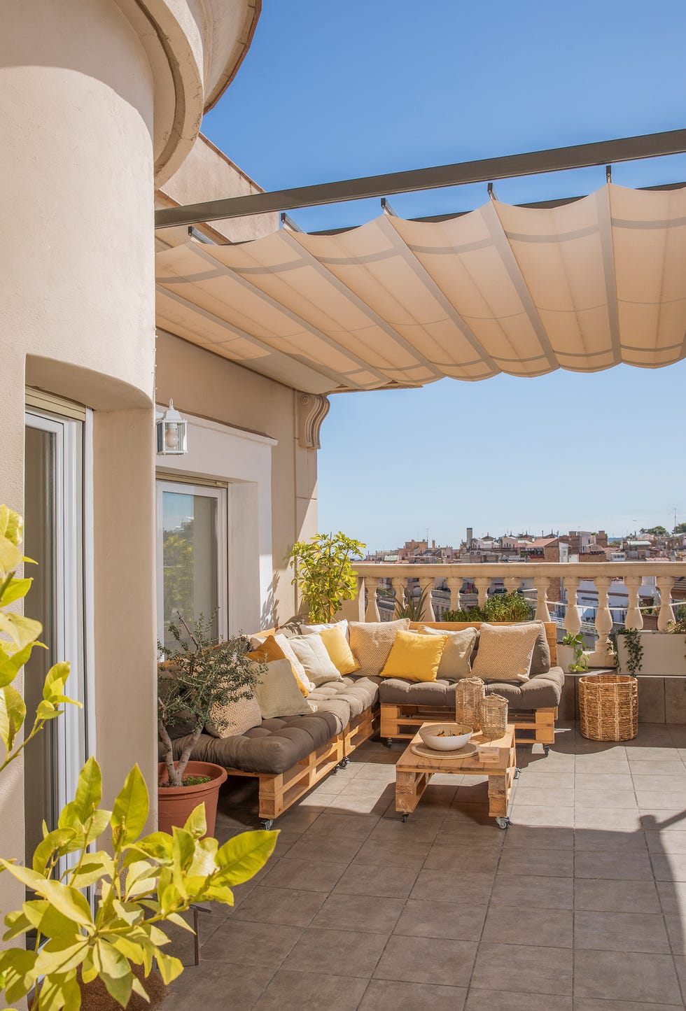 terraza con sofá de palés y toldo