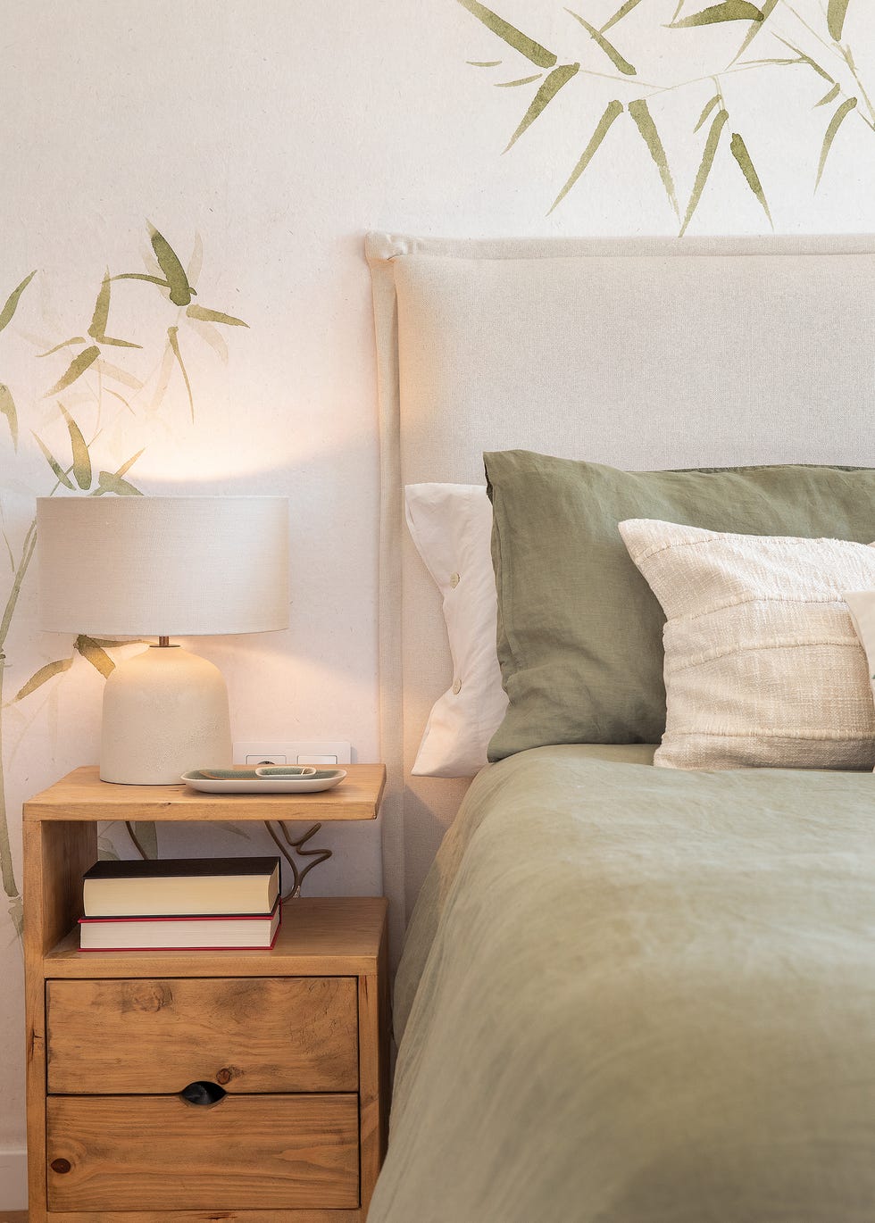dormitorio con papel pintado con motivos botánicos y mesita de noche de madera