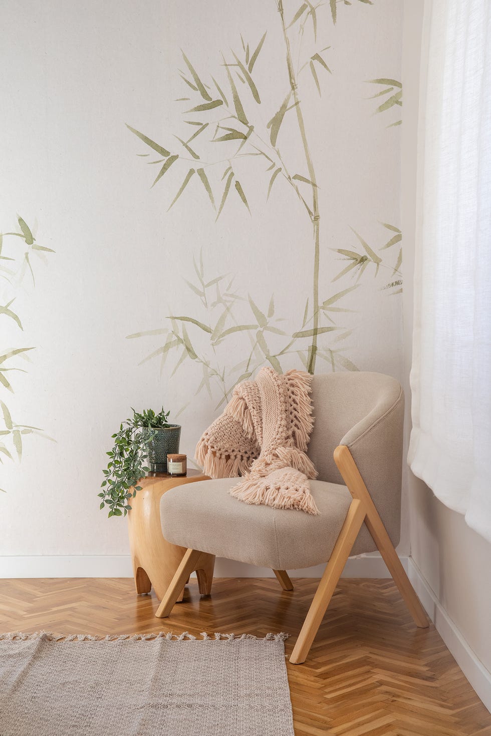 dormitorio con papel pintado con motivos botánicos y butaca tapizada en color beige
