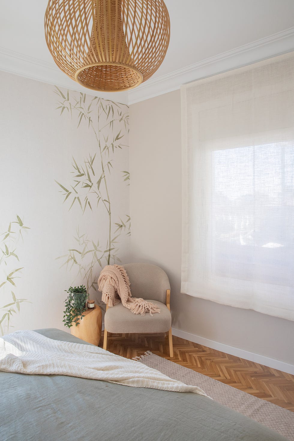 dormitorio con papel pintado con motivos botánicos y butaca tapizada en color beige