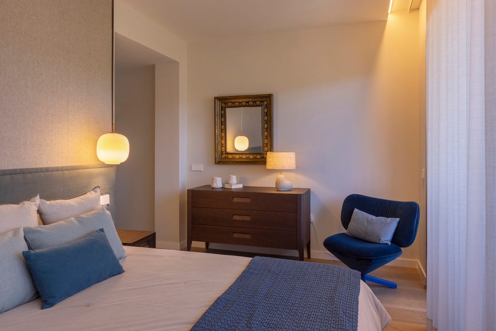 dormitorio con butaca azul y cómoda de madera
