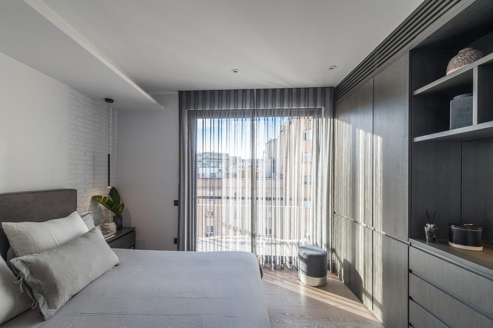 dormitorio moderno decorado en tonos grises con lámparas suspendidas y armarios empotrados
