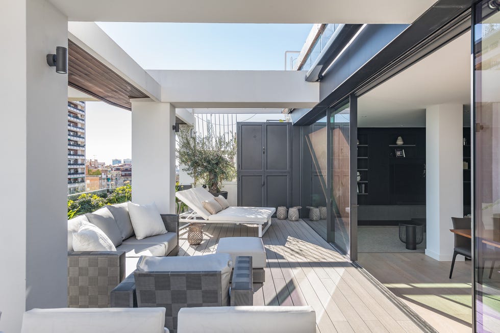 terraza con tumbonas blancas , sillones y un sofá en tonos grises