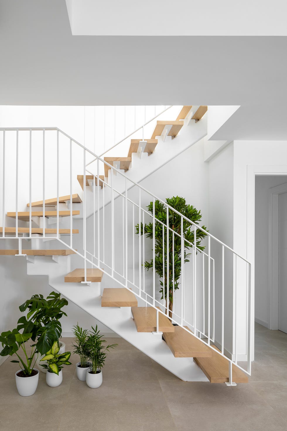 escalera con peldaños flotantes de madera y estructura metálica blanca