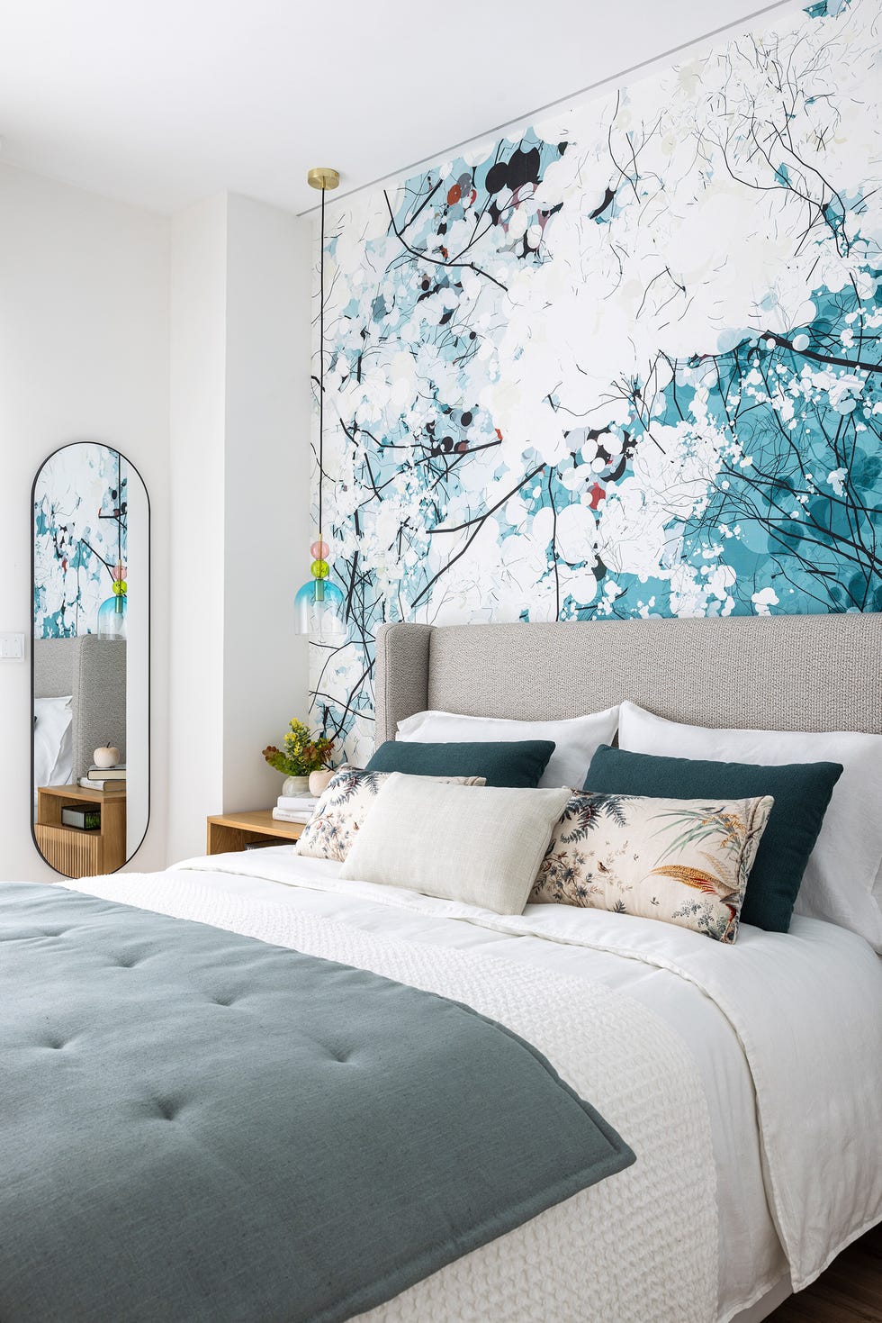 dormitorio con cabecero tapizado en gris y papel pintado con motivos azules
