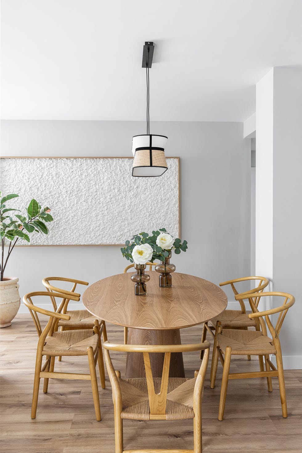 mesa de comedor ovalada con sillas de madera y lámpara suspendida