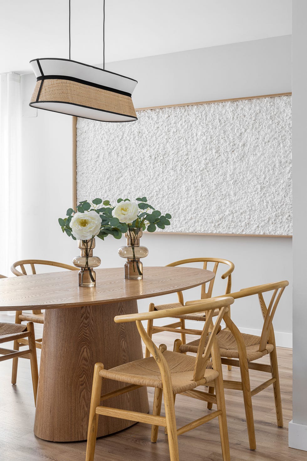 mesa de comedor ovalada con sillas de madera y lámpara suspendida