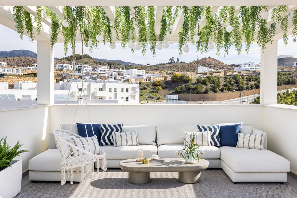 terraza con sofá modular y plantas colgando de la pérgola