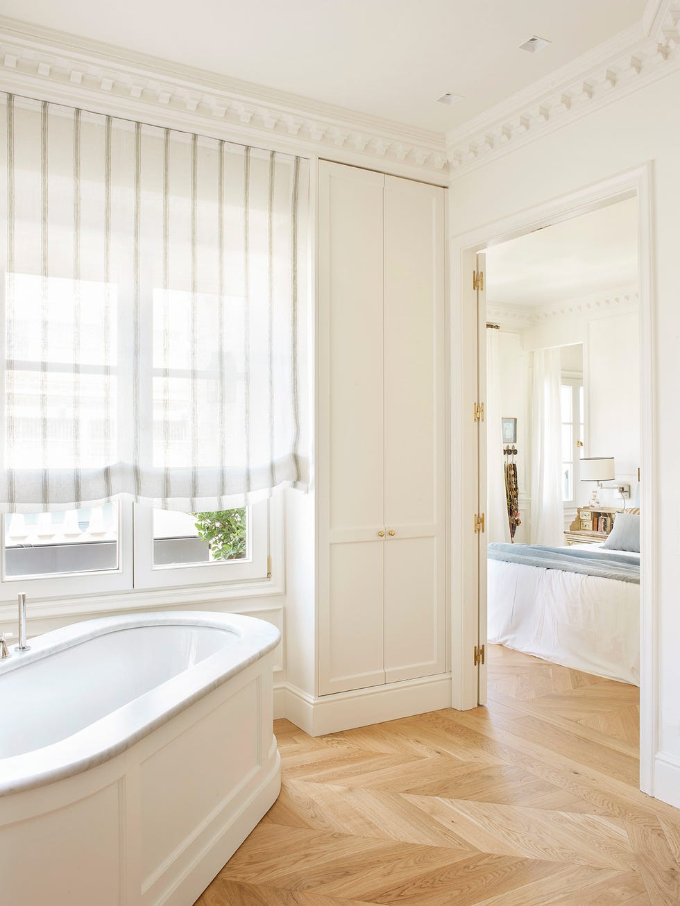 baño en suite con bañera y muebles blancos