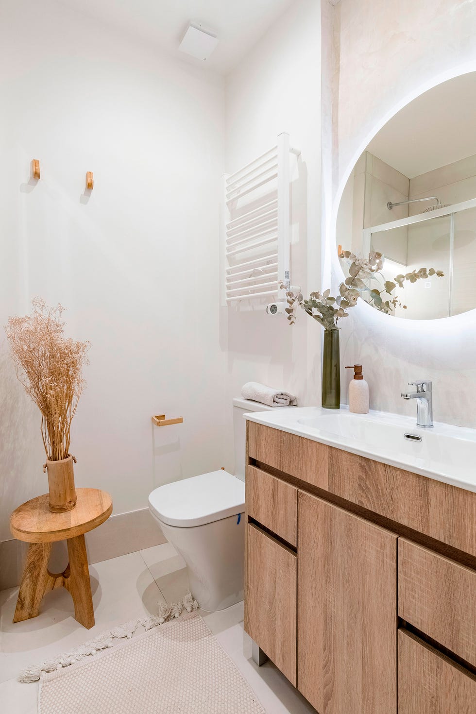 baño con mueble de madera y espejo redondo