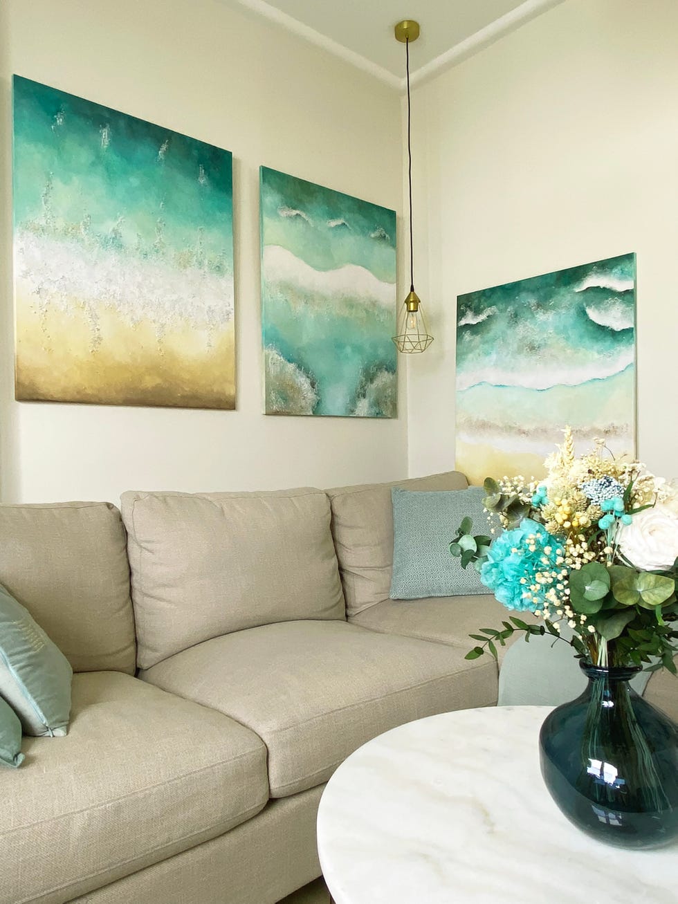 salón con sofá con chaise longue gris y cuadros inspirados en el mar