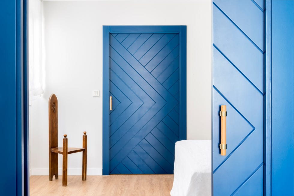 dormitorio con puertas azules y silla de madera antigua