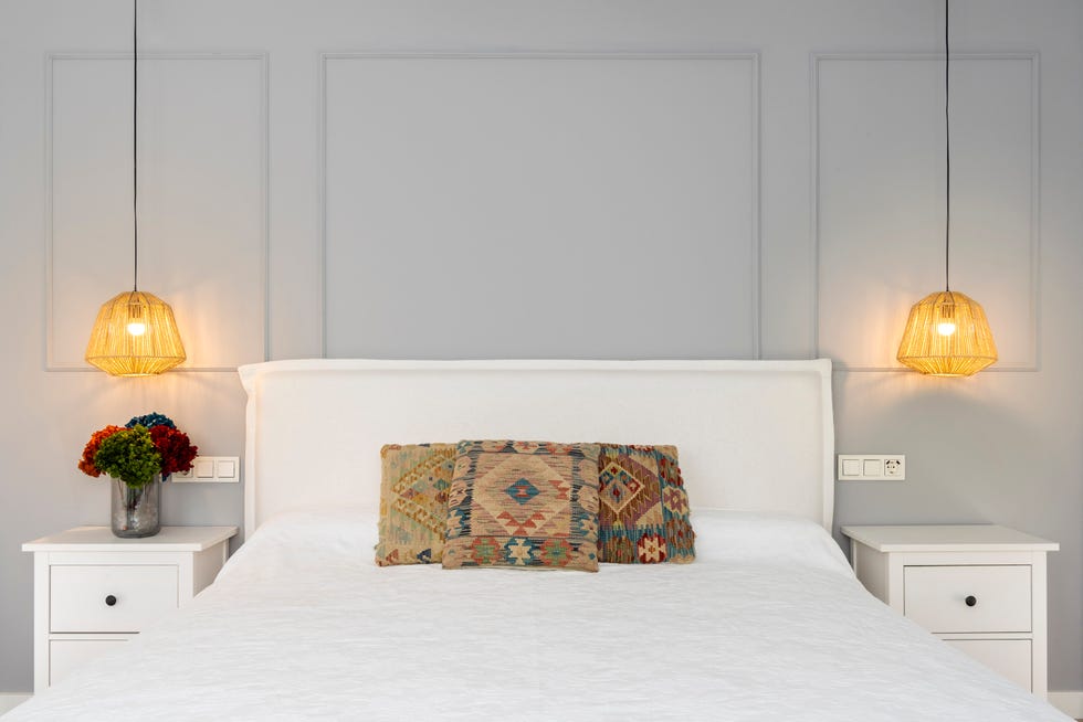 dormitorio con molduras decorativas en las paredes y cabecero de lino