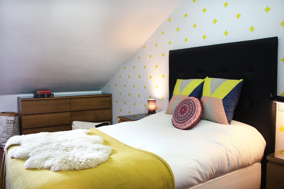 cama con cabecero negro y papel pintado con cruces amarillas
