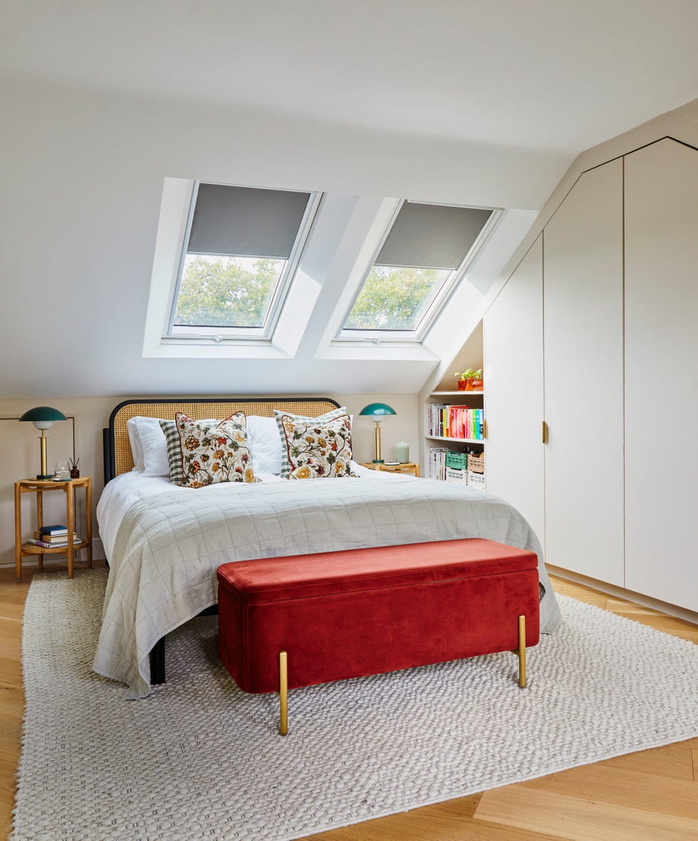attic bedroom with in built in storage in neutral tones with a rattan bed frame and deep russet ottoman