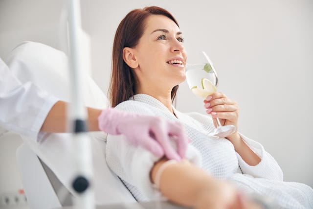 attractive dark haired woman smiling during the intravenous therapy