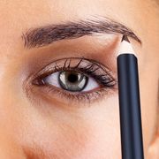 attractive woman applying eyebrow pencil