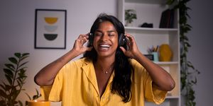 young woman laughing with headphones on at home