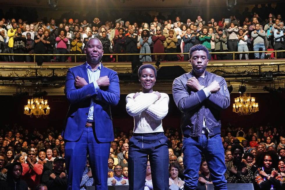 tanehisi coates, lupita nyong'o and chadwick boseman pose with their arms crossed in xs across their chests in a packed theater