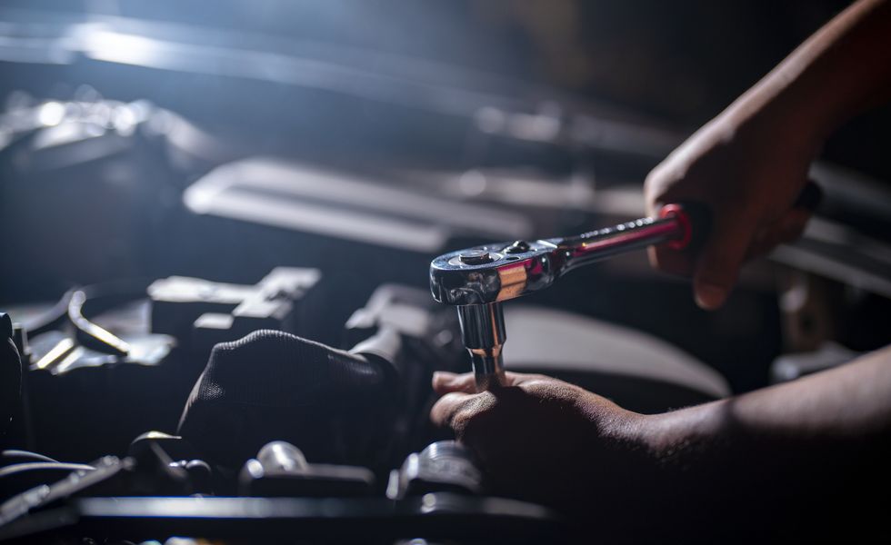auto mechanic working on car engine in mechanics garage repair service  authentic close up shot