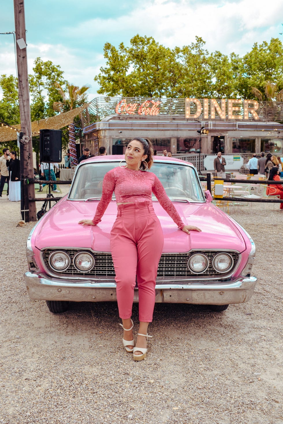 a person posing in front of a pink car