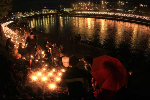 Mensen steken kaarsen aan na zonsondergang tijdens de herfst equinox viering aan de waterkant van de rivier de Neris in Vilnius Litouwen