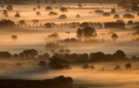 Vroege ochtendmist blijft hangen in de velden terwijl de zon opkomt over de Somerset Levels tijdens de herfst equinox zoals gezien vanaf Glastonbury Tor in Somerset Engeland