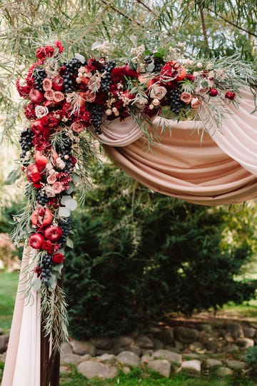 autumnal wedding arch decoration of roses, apples, grape and pomergranate