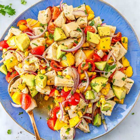 avocado chicken salad with corn, tomatoes, and red onion on a blue plate