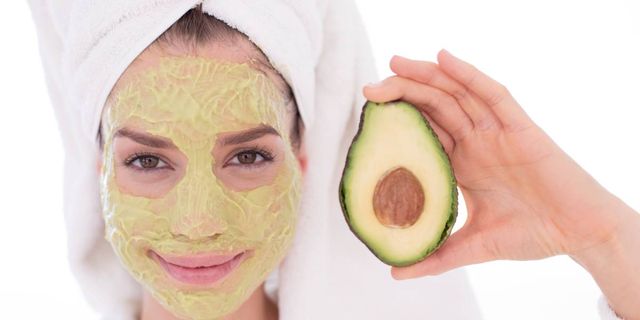 Vrouw met groen gezichtsmasker van avocado