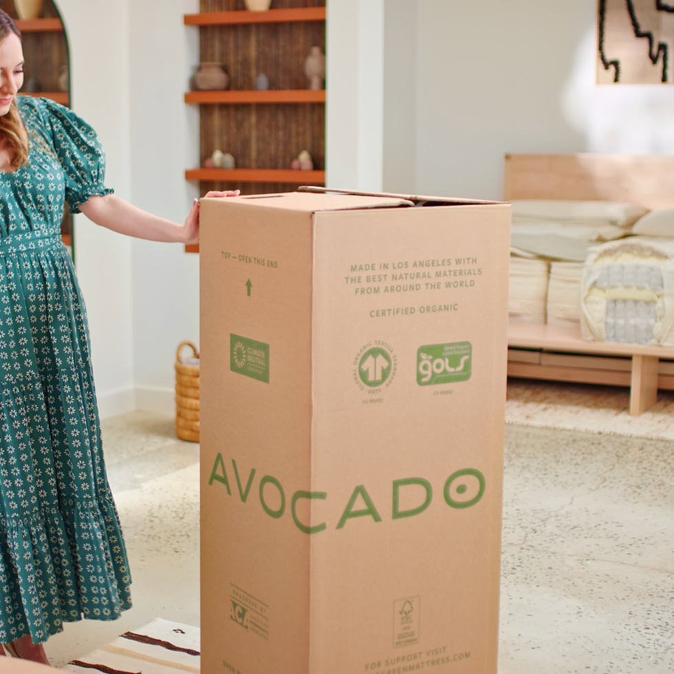best organic mattress - delivery a woman in a dress holding a large mattress box